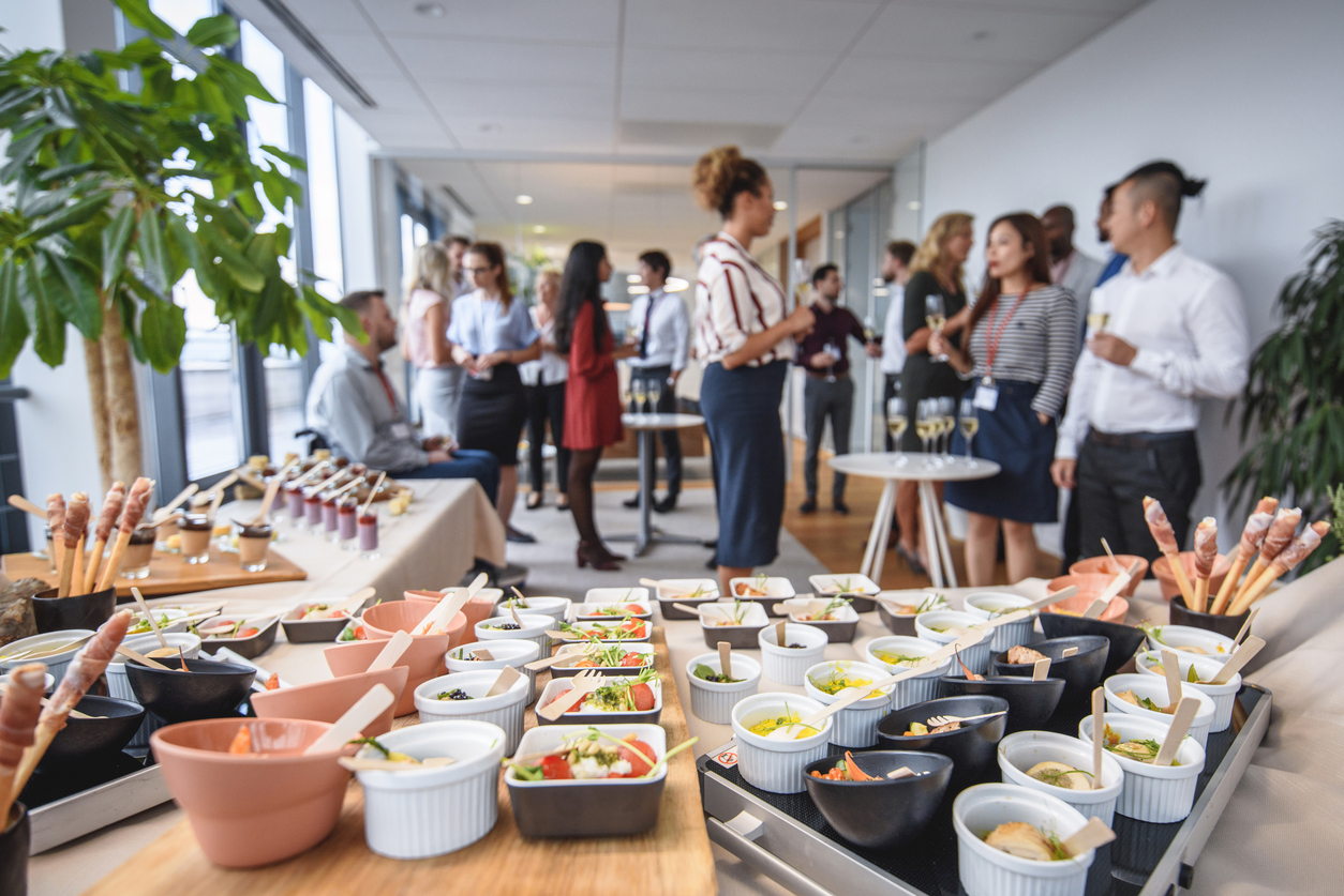 Corporate holiday party - A table filled with food and a group of diverse employees in the background during a company party.